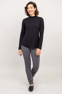 Walking view of a woman in a black mock neck top and slim gray pants