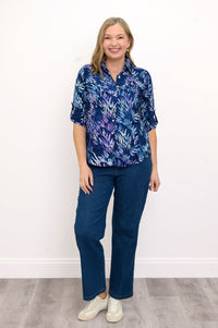 Front view of woman wearing a blue patterned blouse and jeans against a white background