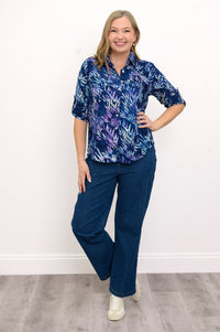 Front view of woman wearing a blue patterned shirt and jeans against a white background