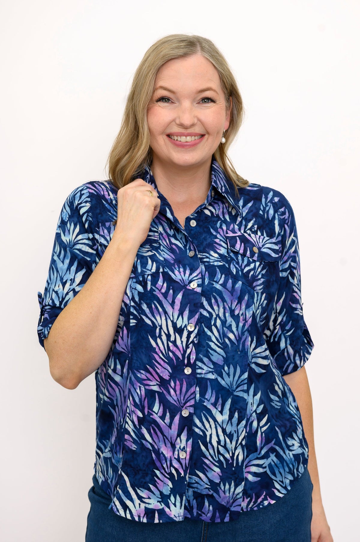 Front view of woman wearing a blue and purple leaf patterned blouse against a white background