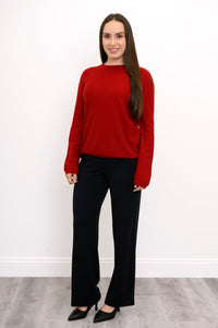 full body front view of woman dressed in long-sleeve red sweater and straight leg black pants