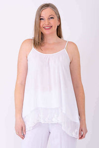Woman wearing a white lace-trimmed tank top with adjustable straps, front view