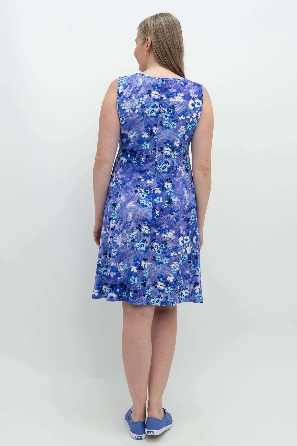 Back view of woman wearing the blue floral dress and blue sneakers