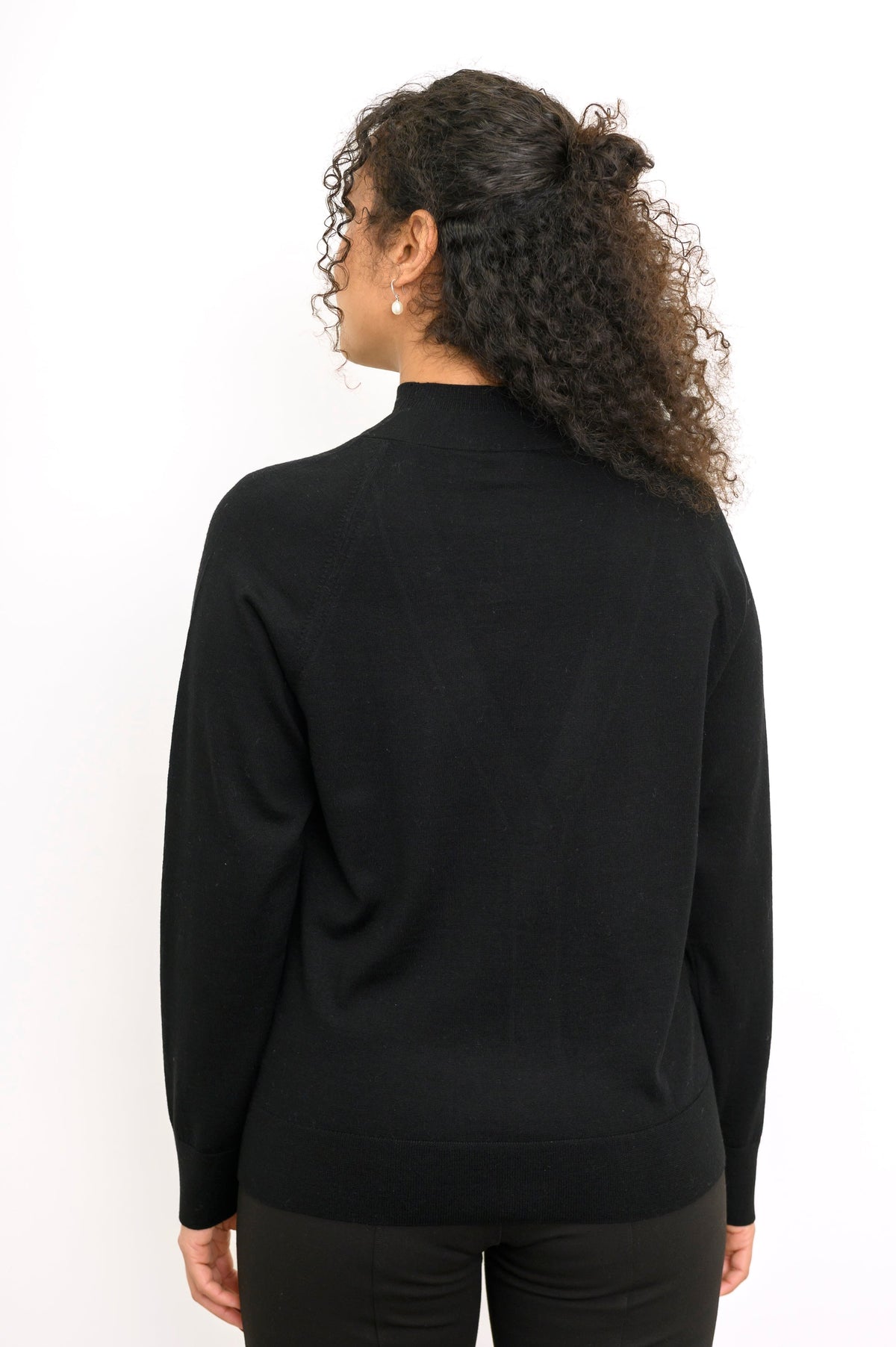 Rear view of a long sleeve black fine wool knit sweater showing clean back fit and ribbed hem.