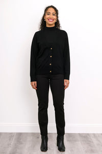 Full length view of a woman wearing a black merino wool v-neck cardigan sweater and black pants.