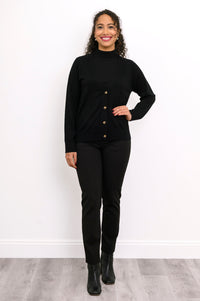 Front view of a woman wearing a black merino wool button down cardigan layered over black pants.