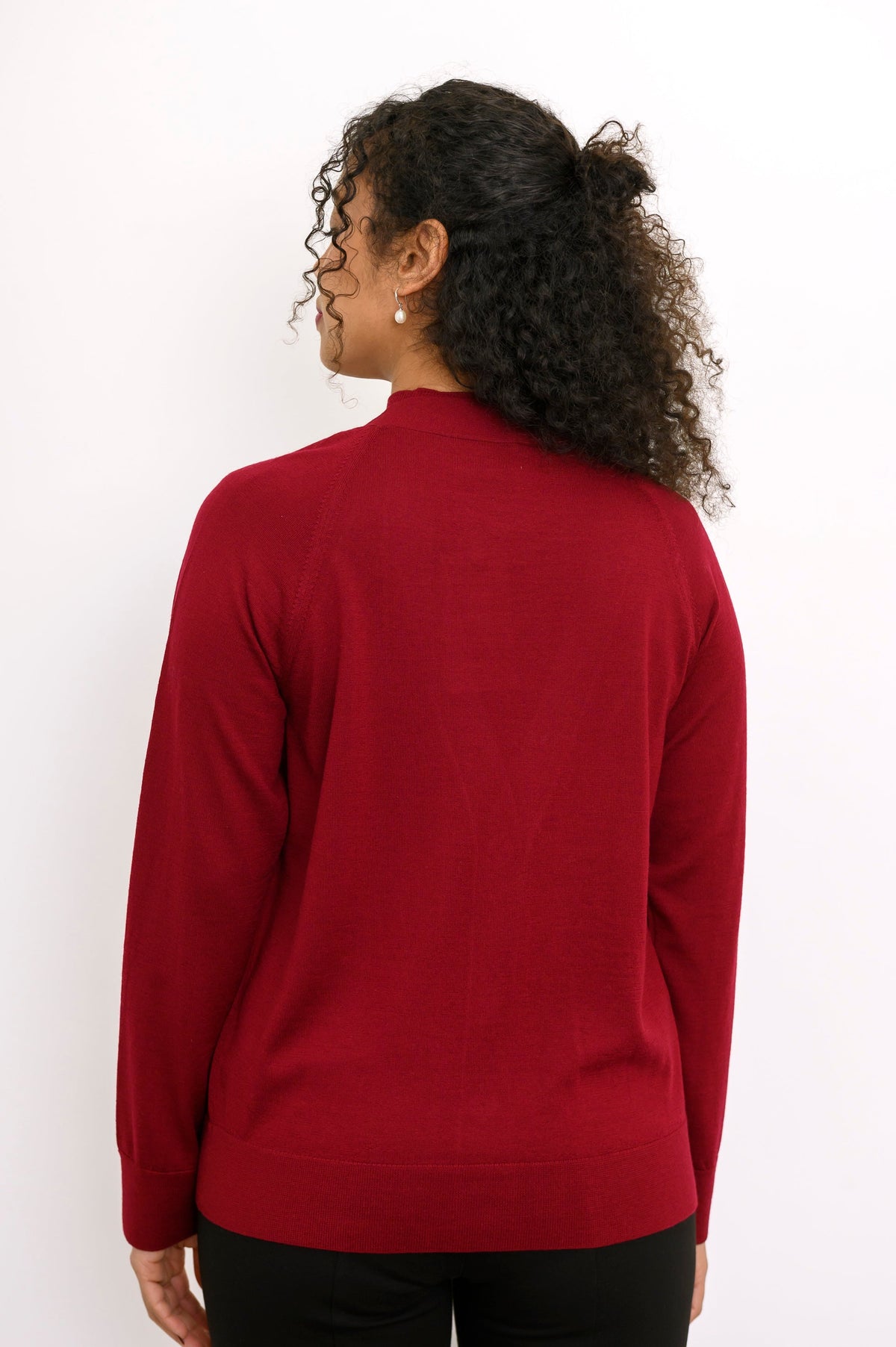 Rear view of a long sleeve dark red fine wool knit sweater showing clean back fit and ribbed hem.
