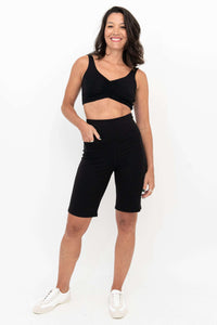 Woman in Leslie black shorts with crop top, hand in pocket, front view