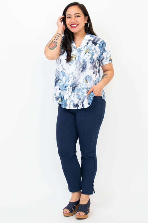 Woman wearing blue floral button-up shirt paired with navy pants and sandals, hand in pocket