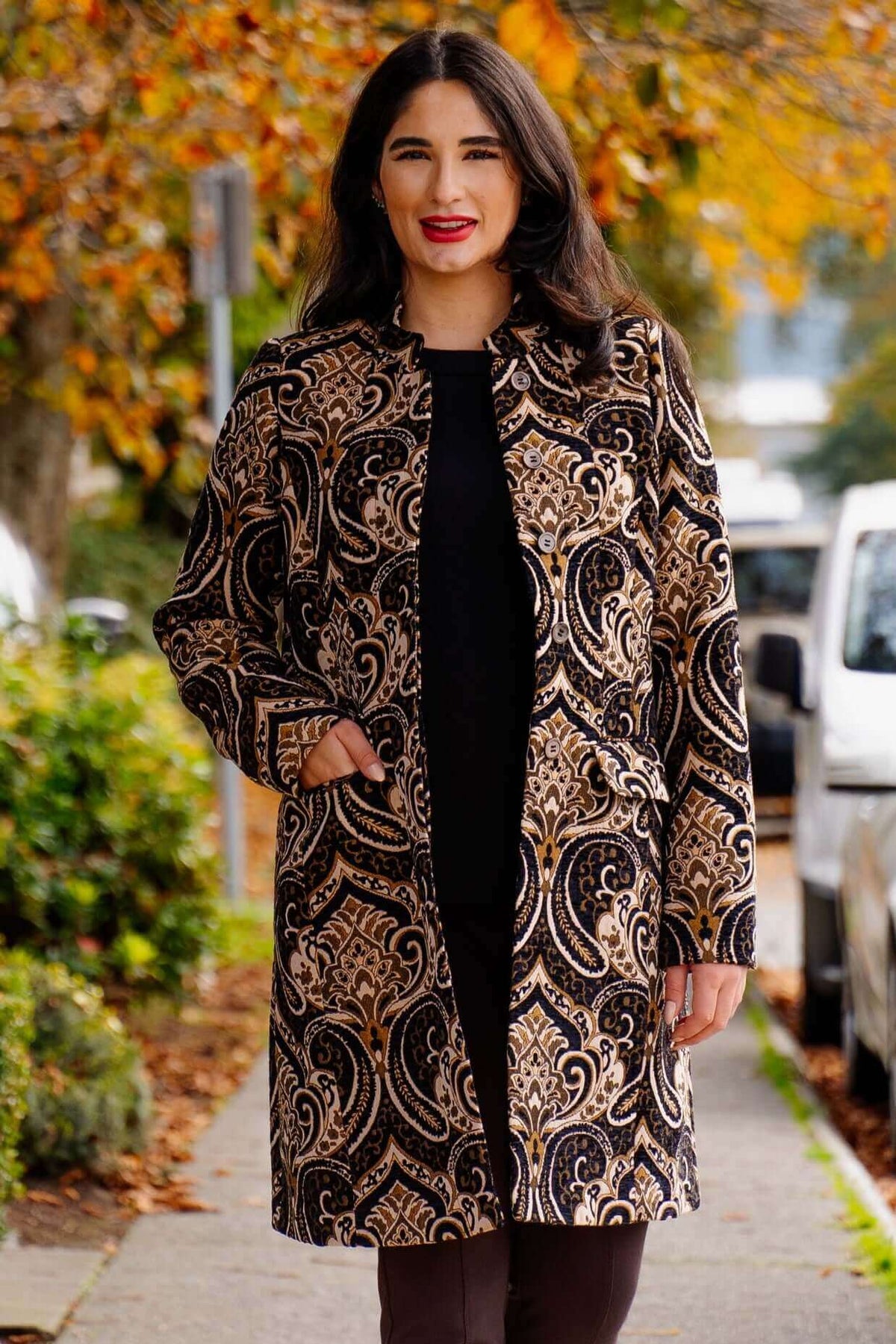 Woman wearing a tailored coat with an ornate jacquard pattern outdoors
