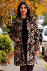 Woman wearing a tailored coat with an ornate jacquard pattern outdoors