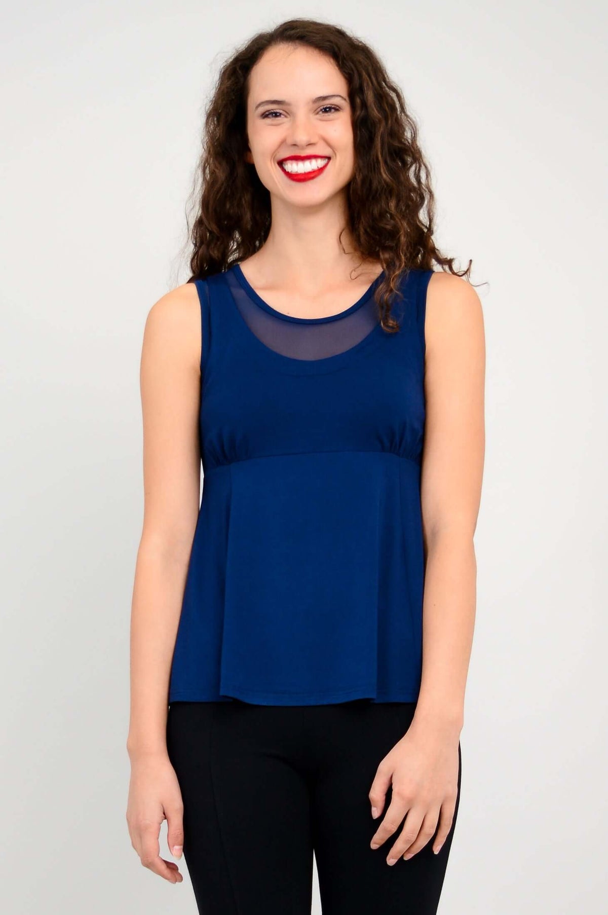 Woman wearing a sleeveless navy tank top with mesh neckline, smiling at the camera