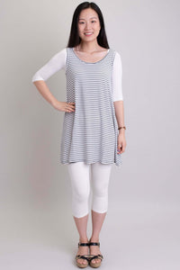 Woman in white Instant Sleeve bamboo bolero, striped tunic, and white capris posing with hand on hip