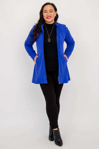 Full front view of woman in cobalt blue zip-up coat, hands in pockets