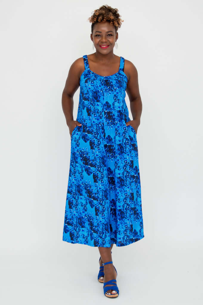 Woman smiling in blue floral jumpsuit with hands in pockets