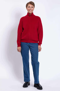 Smiling woman in a red wool-cashmere cardigan, standing with hands at sides
