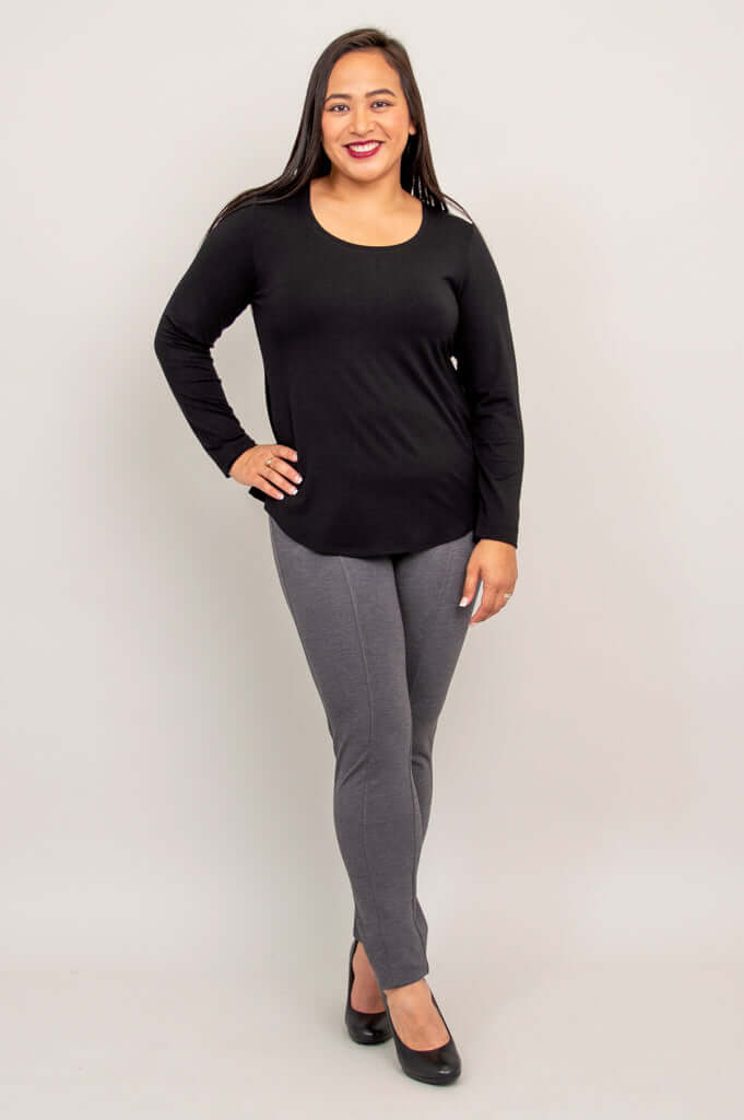 Woman standing in black long sleeve bamboo top and gray pants, angled front view
