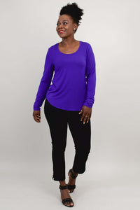 Woman walking in a purple long sleeve scoop neck shirt and black pants