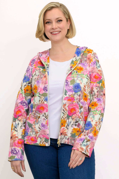 Woman in a vibrant pink floral zip-up hoodie jacket, smiling and standing against a white background