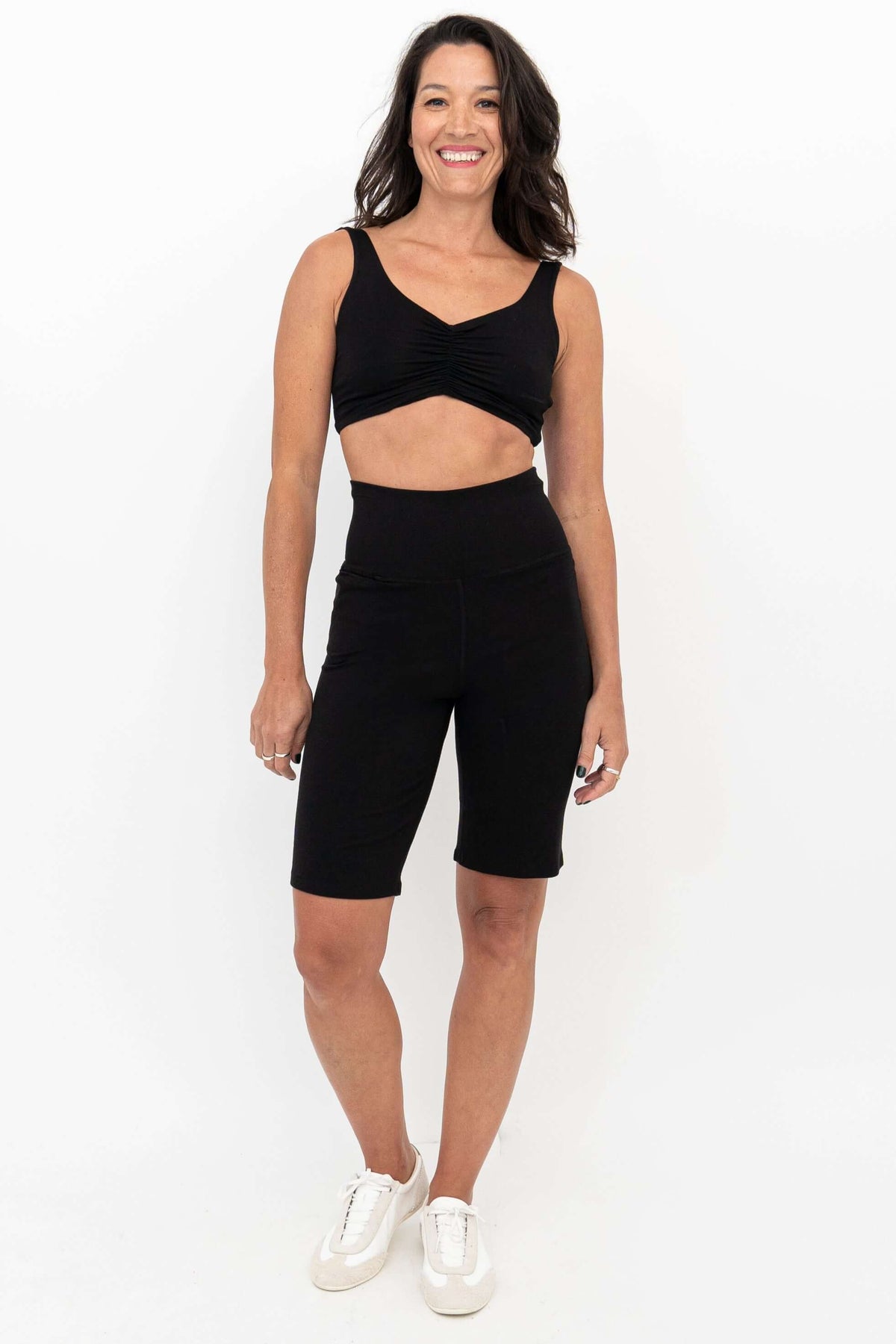 Woman wearing Leslie black shorts and crop top, front view