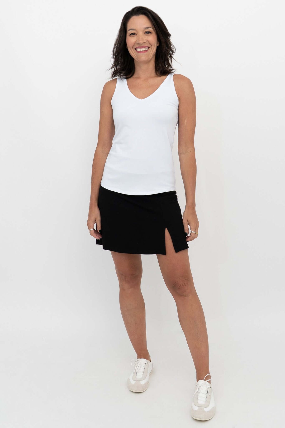 Woman wearing black Melly skort and white tank, facing front