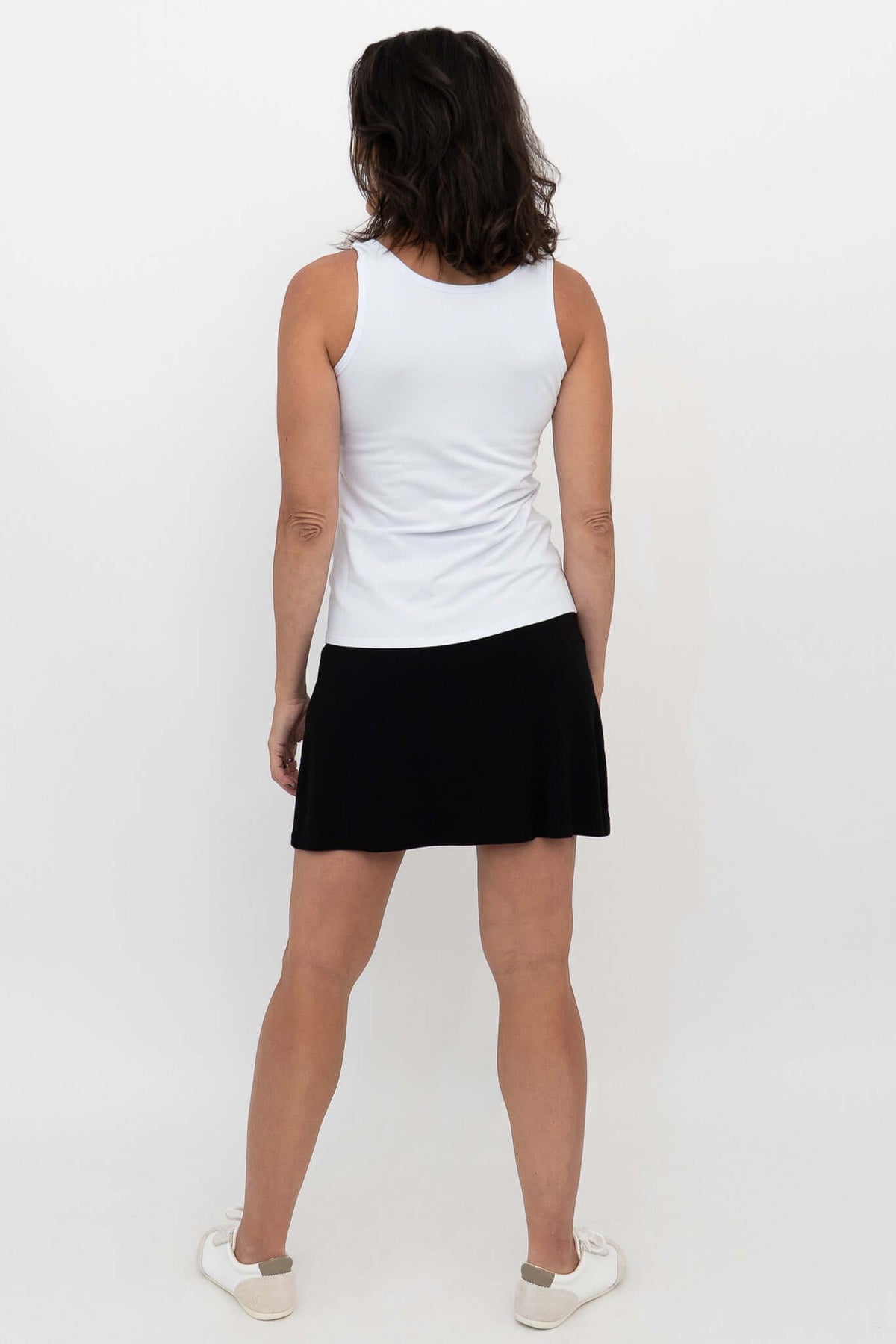 Woman wearing black Melly skort and white tank, shown from the back