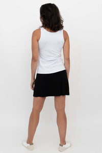 Woman wearing black Melly skort and white tank, shown from the back