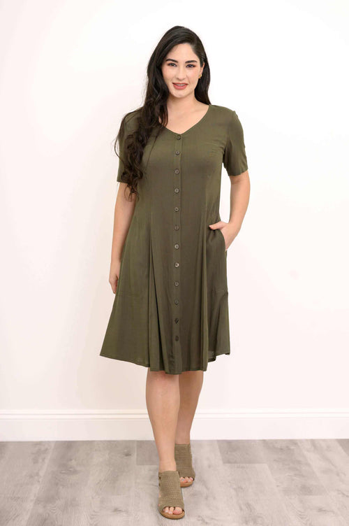 Woman wearing olive button-front dress with short sleeves and pockets, standing on wood floor