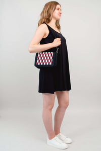 Woman with geometric embroidered crossbody bag, wearing a black dress