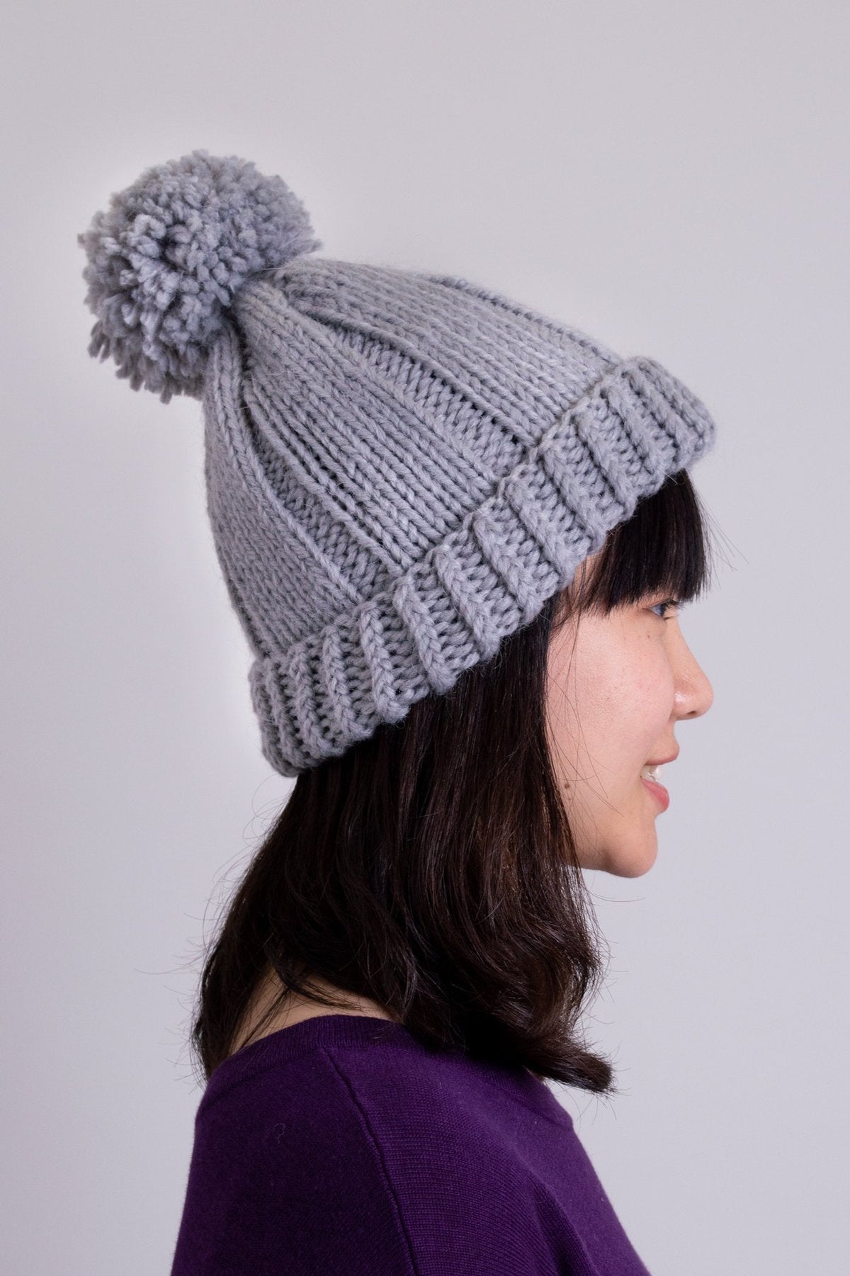 Women's grey knit toque wool hat with pompom.