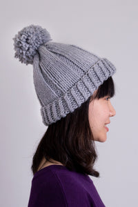 Women's grey knit toque wool hat with pompom.