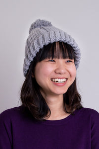 Women's grey knit toque wool hat with pompom.